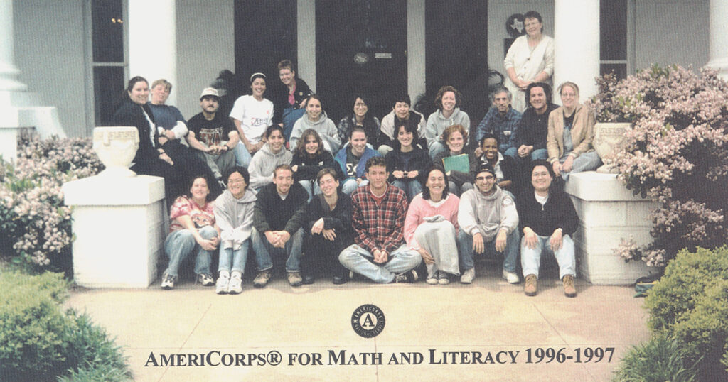 A portrait of a cohort of AmeriCorps tutors sitting on steps outside of a building. At the bottom, text says "AmeriCorps for Math and Literacy 1996-1997" with the AmeriCorps logo. 