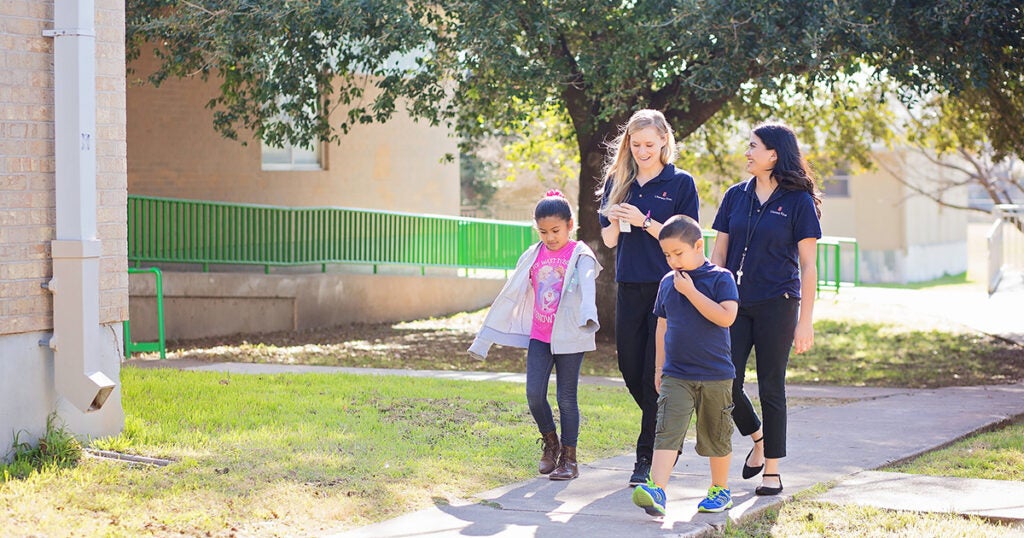 Two tutors and two students are pictured outside, walking on a sidewalk back to class. 