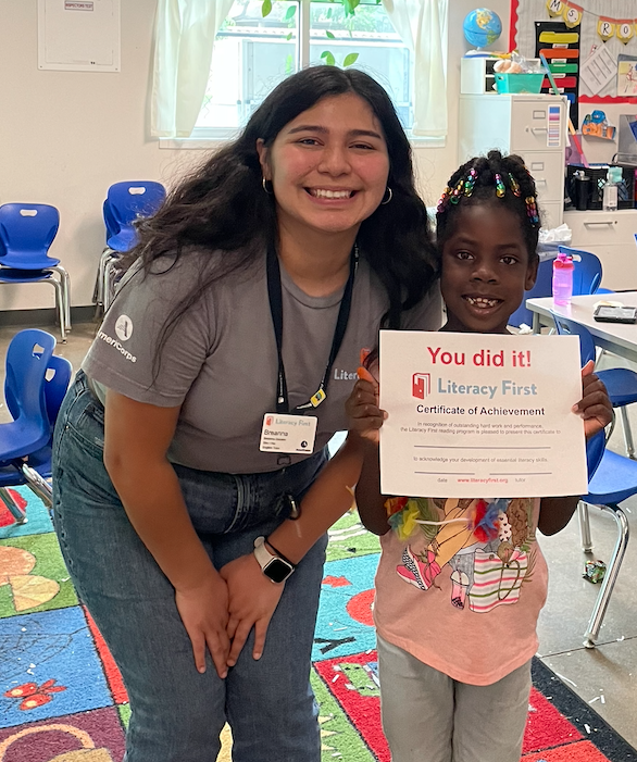 A tutor poses with a student holding a certificate that says "You did it!". 