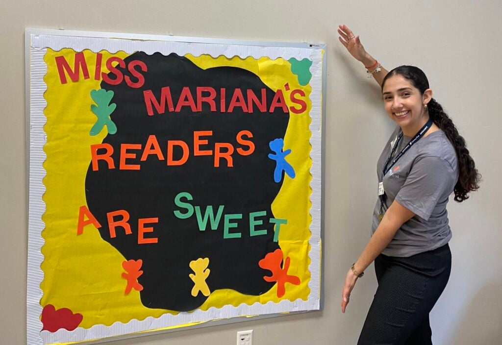 A woman stands next to a bulletin board that says "Miss Mariana's readers are sweet"